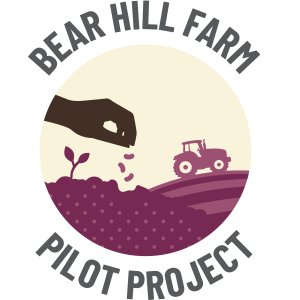 Bear Hill Farm Pilot Project logo. A silhouette of a hand drops seeds into the soil with a tractor on a field in the background.