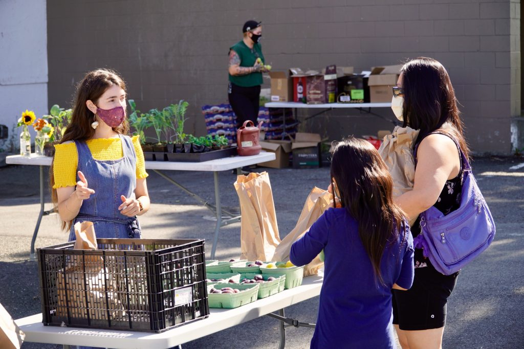 Staff member giving out pre-packaged produce on community sharing day.