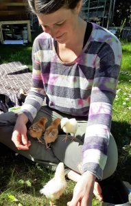 Katie sitting in the grass with baby chickens in her lap