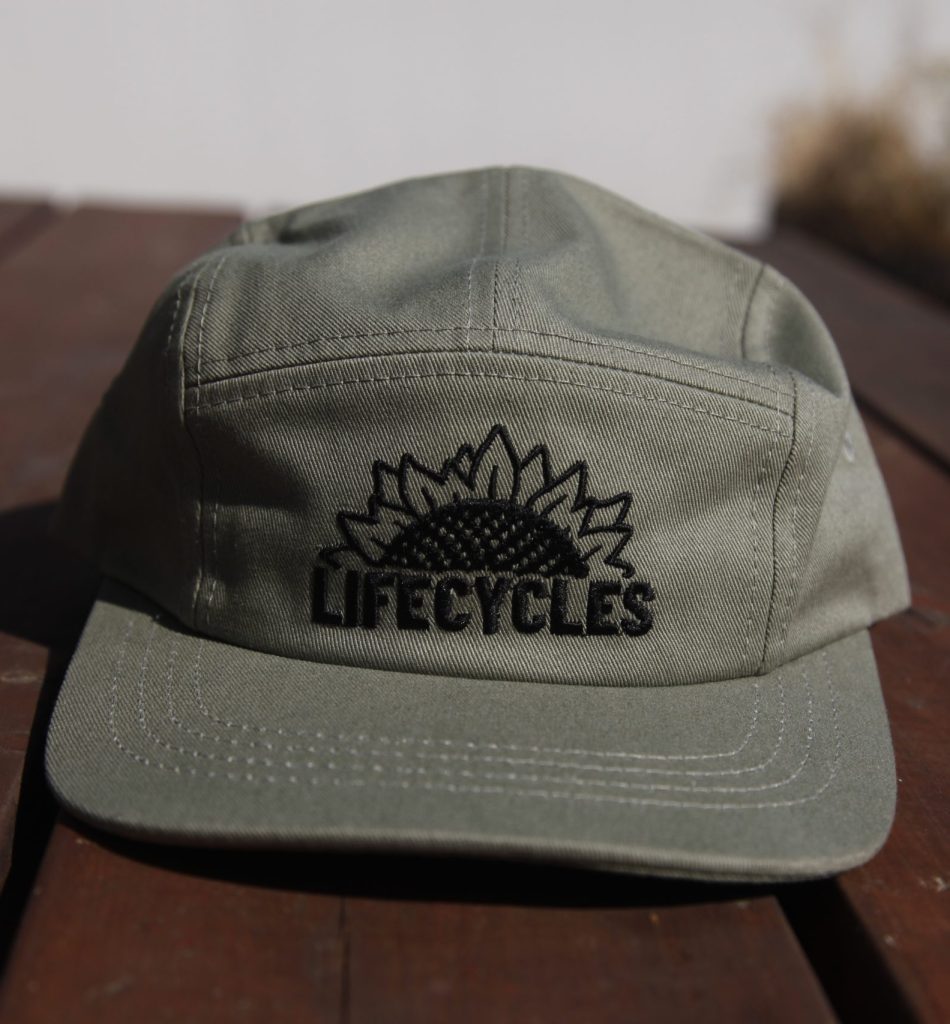 A green five-panel cap with the LifeCycles logo in black on the front.
