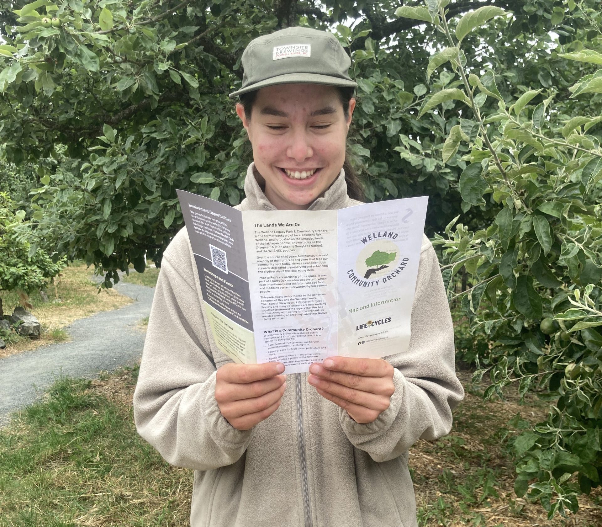 Welland Orchard Volunteer Holding and Reading the 2025 Brochure